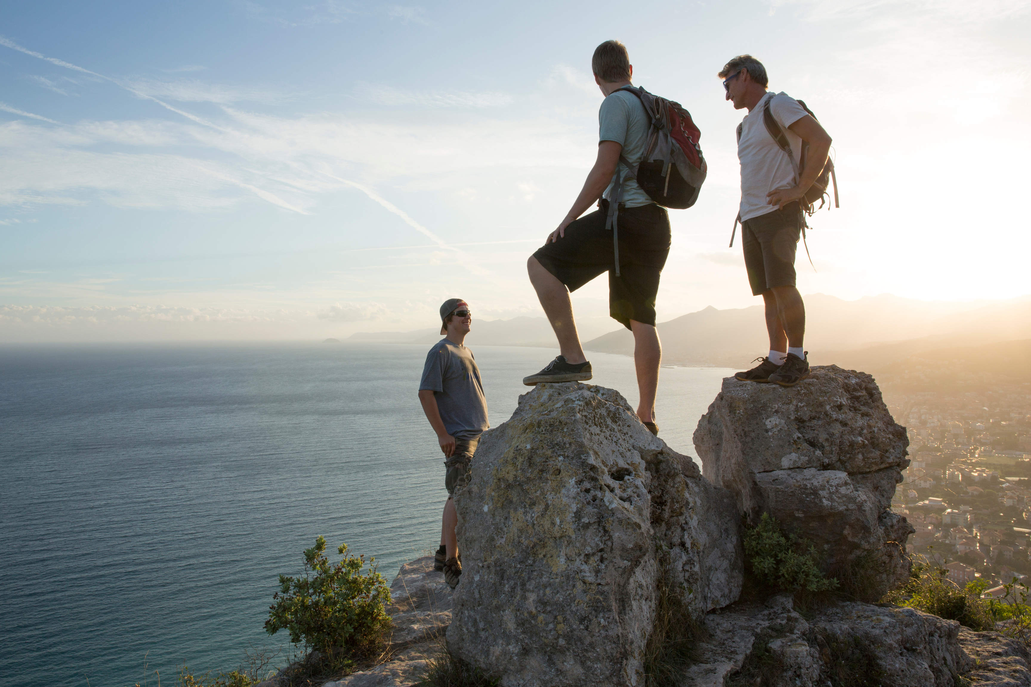 Three men exchange conversation at top of hike