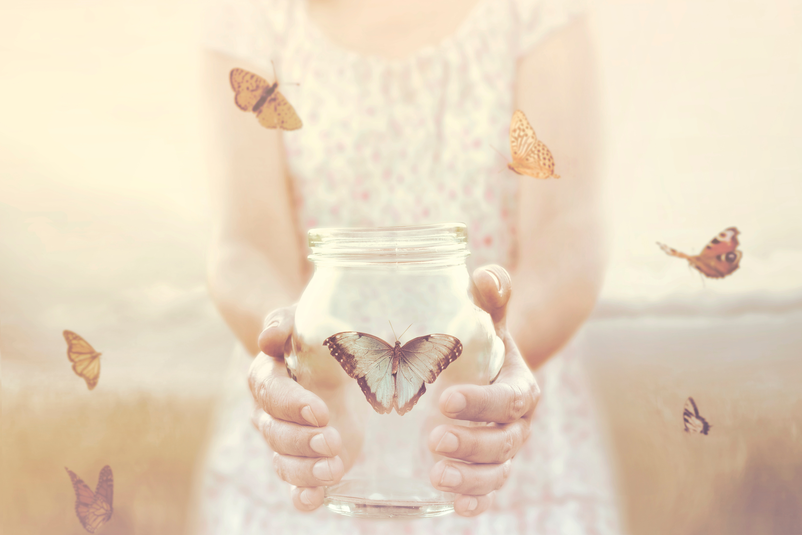 woman gives freedom to some butterflies enclosed in a glass vase