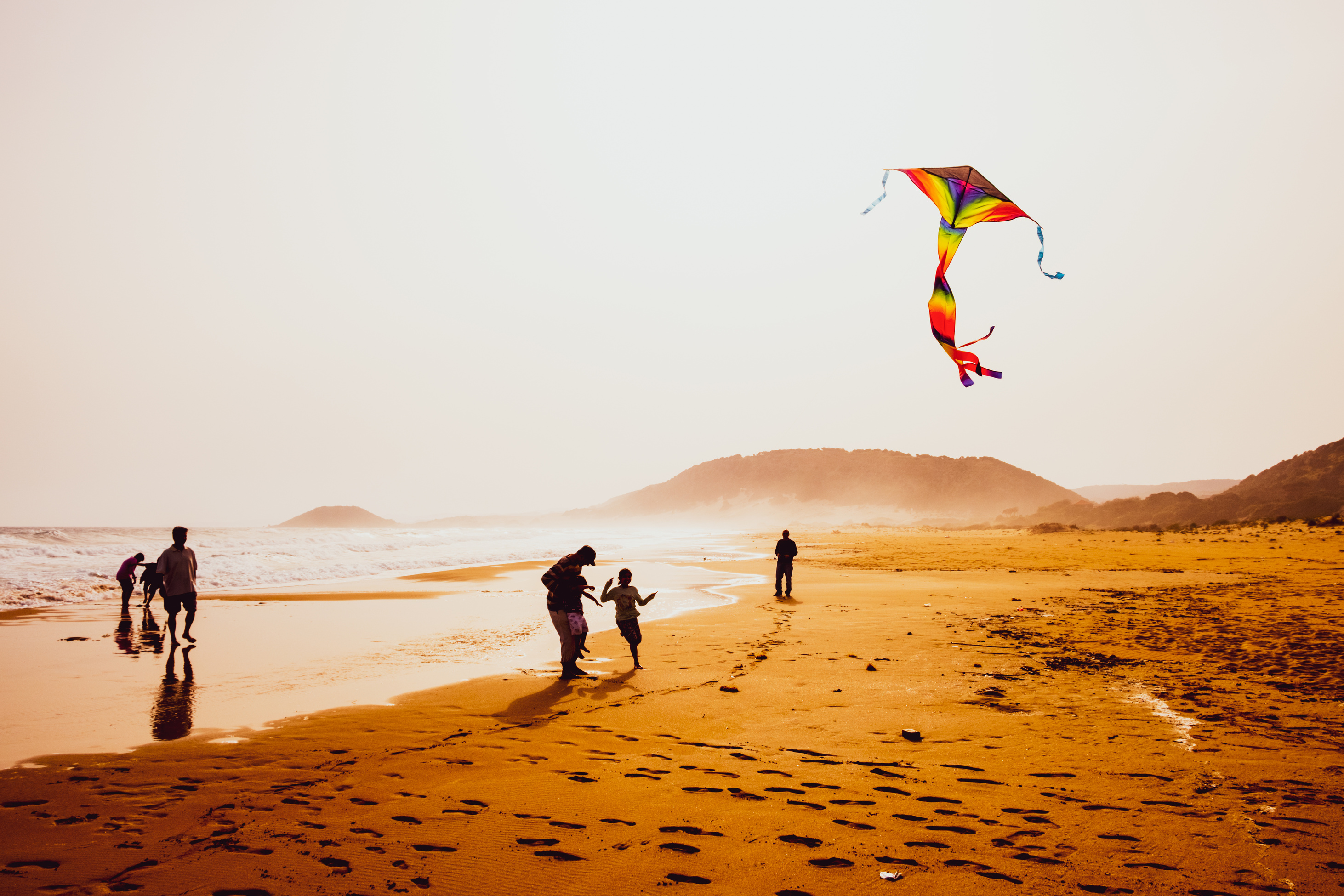 Silhouettes of People Playing and Flying a Kite